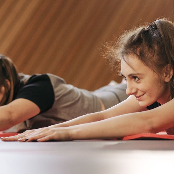 Diverse group of people smiling and preparing for a yoga class in a bright studio.